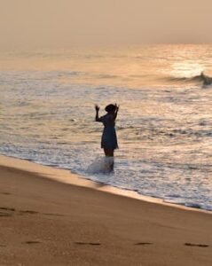 A person enjoys a tranquil moment at the sandy beach of Ouidah, Benin at sunset.